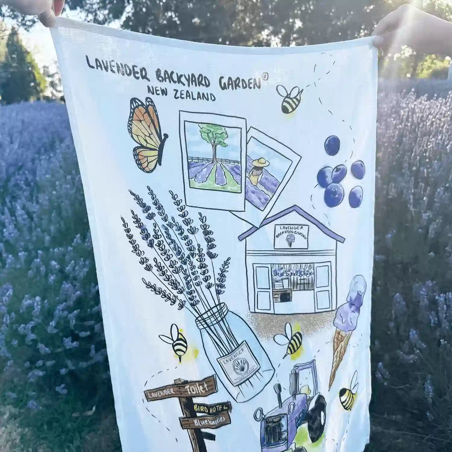 100% linen tea towel designed by New Zealand Lavender Farm, Lavender Backyard Garden, featuring its real fruit ice cream, farm shop, lavender field, lavender and blueberry activities, and iconic purple tractor.