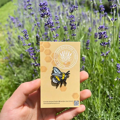 Cute bee enamel pin badge showcased against a vibrant lavender field background, celebrating the essence of a lavender farm.