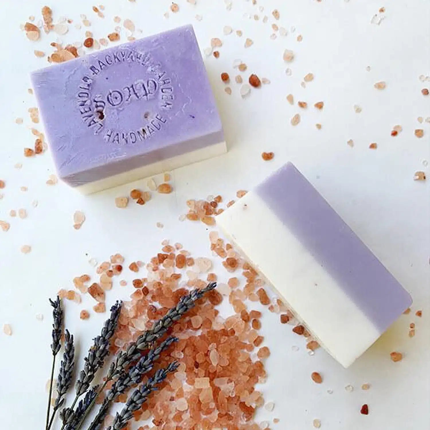 Lavender Scrub Soap decorated with Himalayan salt and dried lavender, set against a soft lavender-colored background.