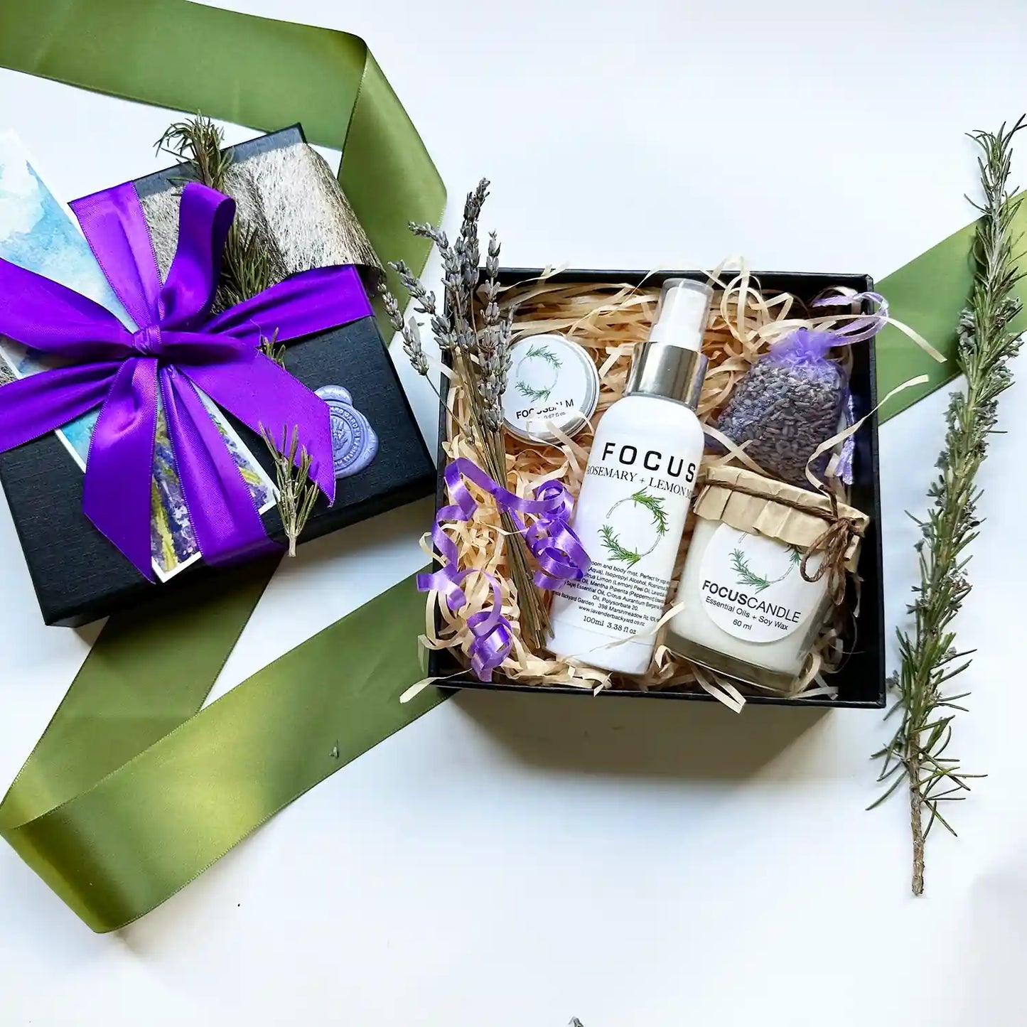 Mind Boost Study Kit Gift Set featuring focus balm, focus mist, and a focus candle scented with rosemary essential oil, along with a lavender sachet, all elegantly wrapped in a black gift box with a purple ribbon.