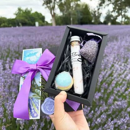 Amazing Bath Spa Gift Sets - Small Gift Boxes, featuring Floral Bath Salts Tube, Dried Lavender Sachet, Lavender Essential Oil Bath Bomb (40mm), and Lavender Field Bookmark against a lavender blooming field.