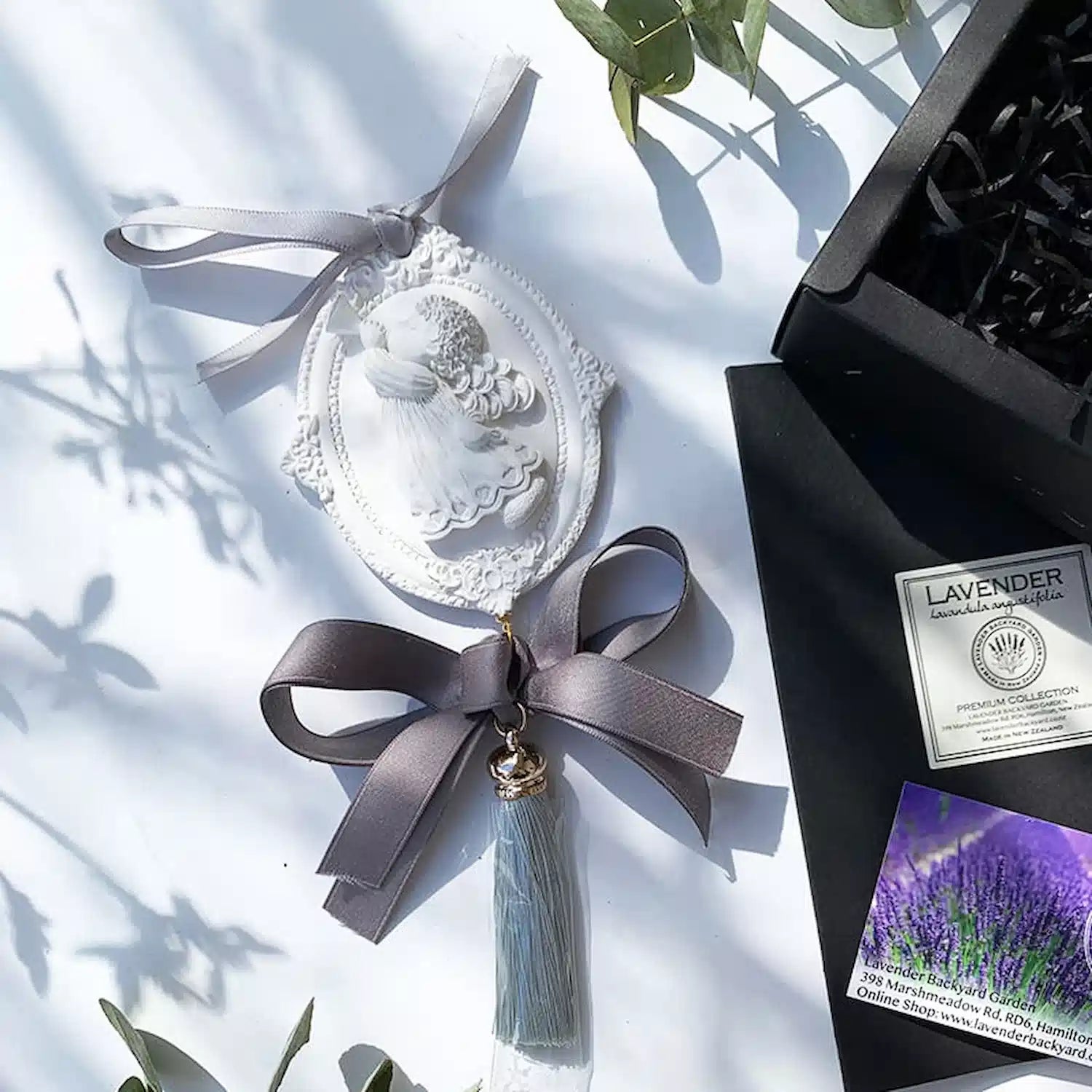 Angel-shaped scented stone diffuser accompanied by a sleek black gift box, with soft shadows adding depth and elegance.