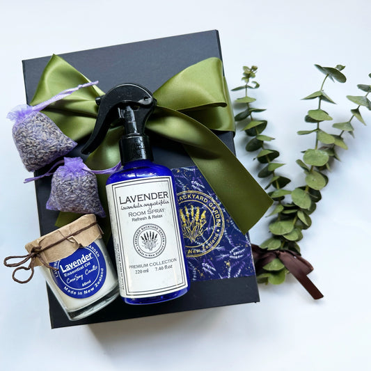 Aromatherapy Care Package for Dad gift set featuring essential oil-scented products including Room Mist, Soy Wax Candle, and dried lavender sachet, presented in a black gift box with a green ribbon and a eucalyptus bundle