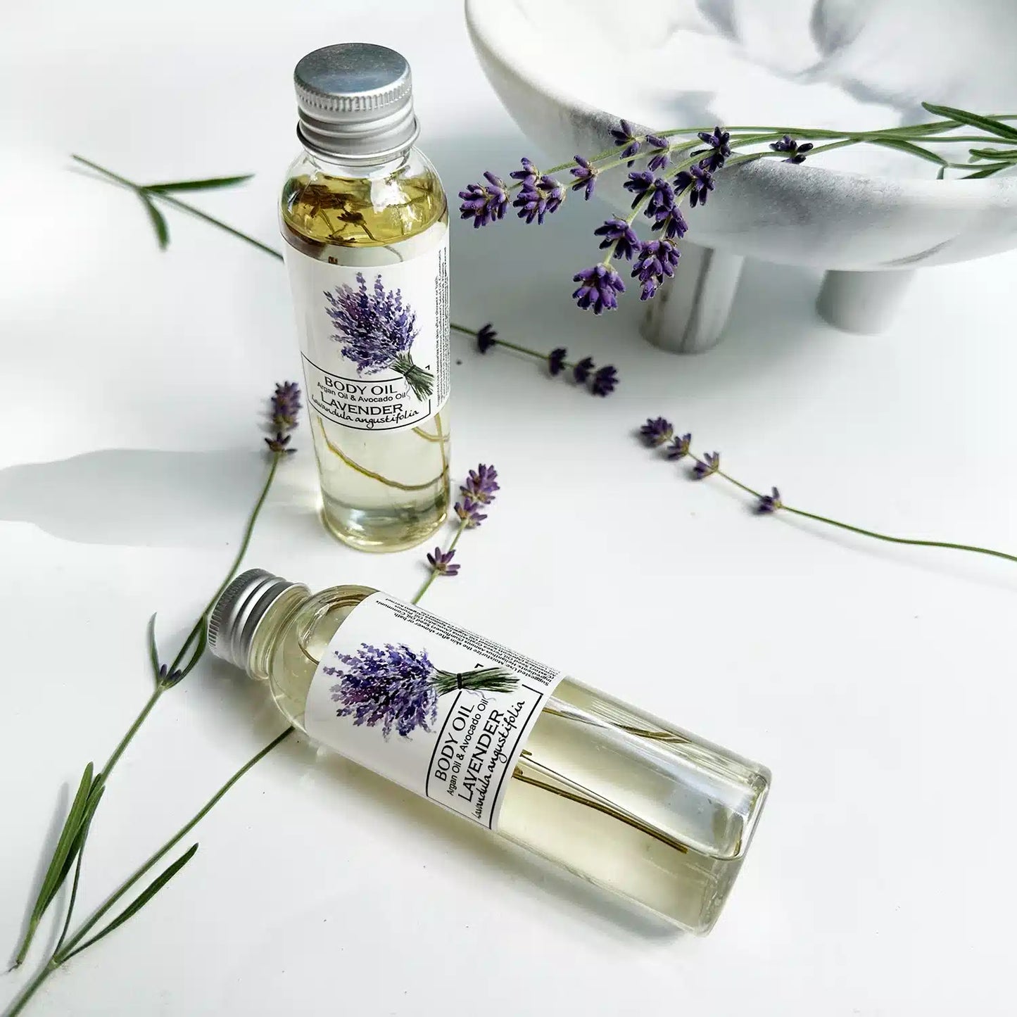 Aromatherapy Lavender Body Oil with argan oil, set against a marble-patterned background and fresh lavender, emphasizing soothing and relaxing benefits.