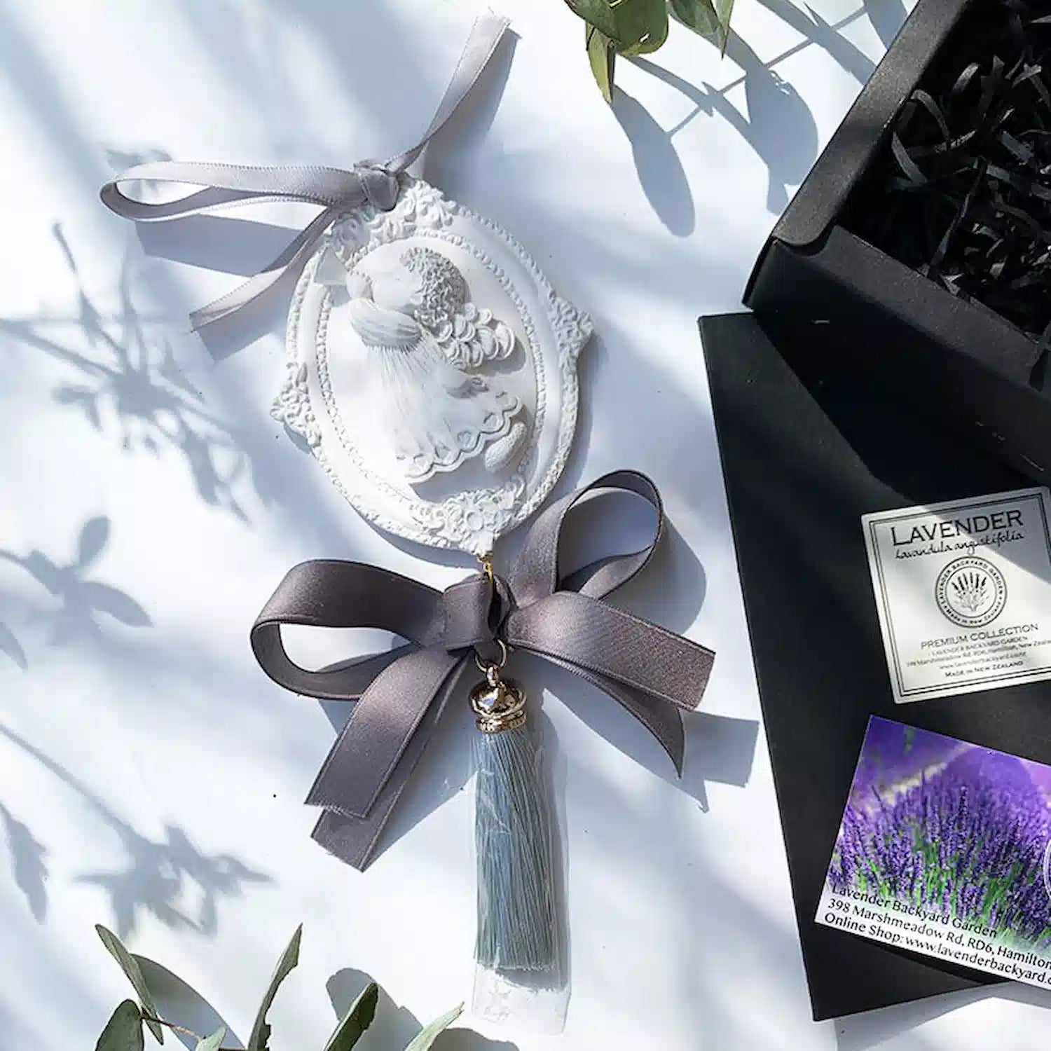 A lavender aroma stone diffuser for cars, decorated with natural eucalyptus leaves. The diffuser casts a soft shadow, adding a touch of elegance to any car interior.