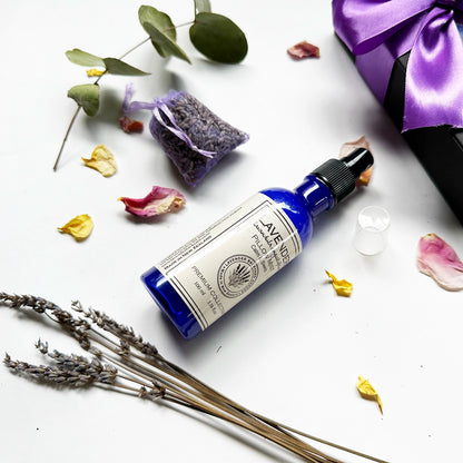 Close-up view of "Lavender Essential Oil Pillow Mist, Dried Lavender Sachet" with rose petals and lavender dried flowers as decor, featuring a purple ribbon black gift box in the background.