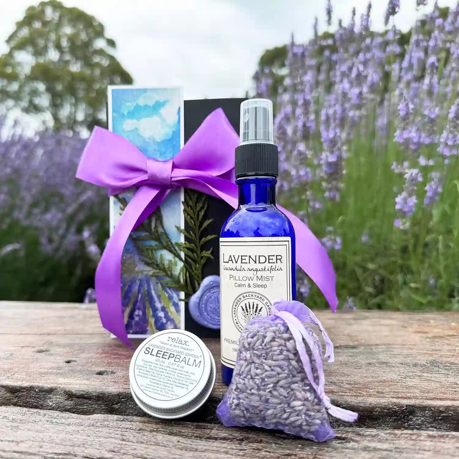 Calming Good Night Sleep Gift Box featuring Lavender Sleep Balm, Lavender Sleepwell Pillow Mist, Dried Lavender Sachet, and Lavender Field Bookmark, displayed against a serene lavender field backdrop.