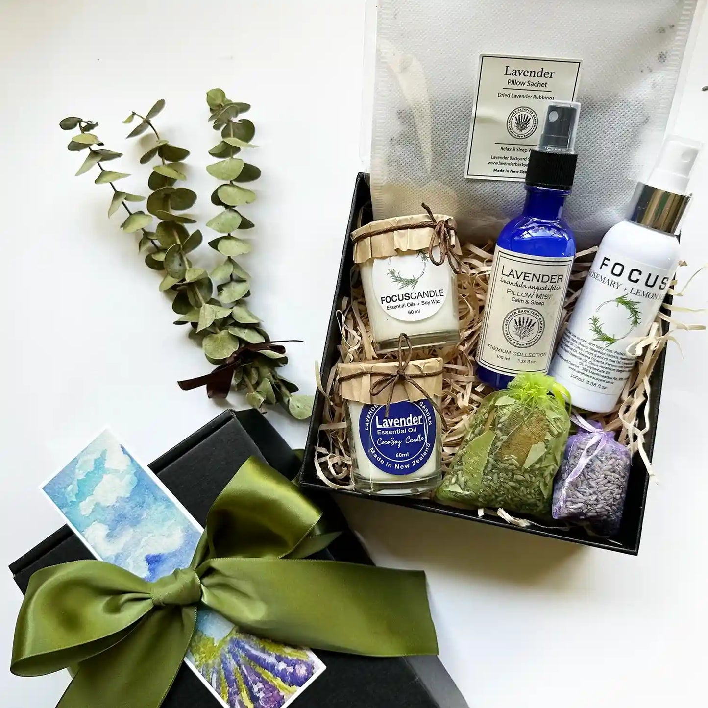 Calming Sleep Gift Set for Him featuring a lavender soy candle, rosemary soy candle, sleep spray, focus mist, sleep pillow sachet, dried lavender sachet, and eucalyptus sachet, all elegantly wrapped with a green ribbon and accompanied by a dried eucalyptus bundle.