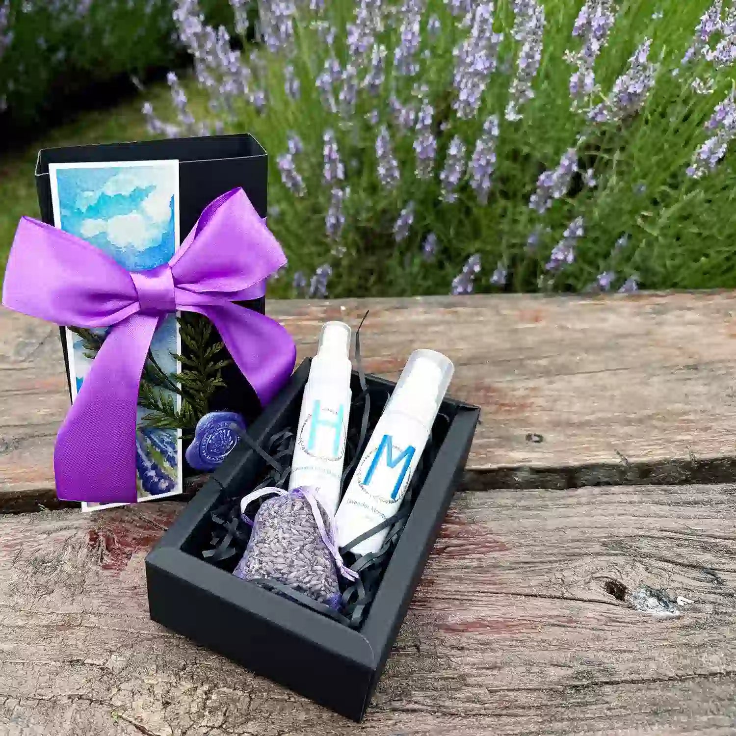 Charming Bridesmaid Gift Box scented by lavender essential oils, featuring Moisturizing Lavender Body Lotion, Lavender Hydrosol Floral Water Face Toner, Dried Lavender Sachet, and Lavender Field Bookmark, placed on a wooden bench against purple lavender bloomings.