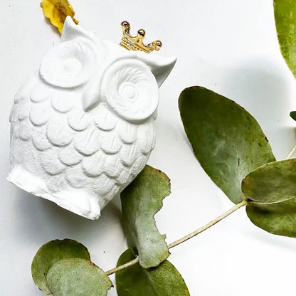 Close-up view of an owl aroma stone freshener, decorated with eucalyptus leaves and yellow roses.