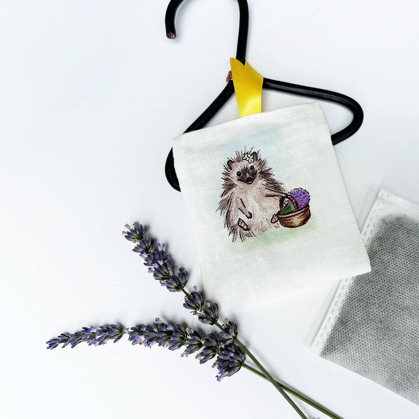 Farm animal hedgehog linen sachet for drawers with a background of fresh lavender flower stems and inner plain sachets pack.