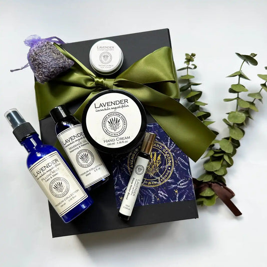 Father's Day Relaxing Massage Box in a green ribbon gift box featuring a lavender sachet and lavender essential oil-scented products, including massage oil, pillow mist, lip balm, hand cream, and sleep roller blend, adorned with a small eucalyptus bundle.