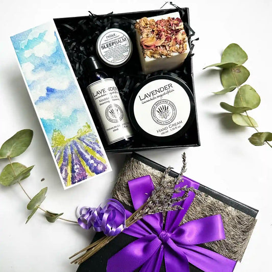 Hand & Massage Therapy Gift Set featuring massage oil, hand cream, sleep balm, and handmade soap all scented with lavender essential oil, beautifully wrapped with a purple ribbon and a lavender field bookmark.