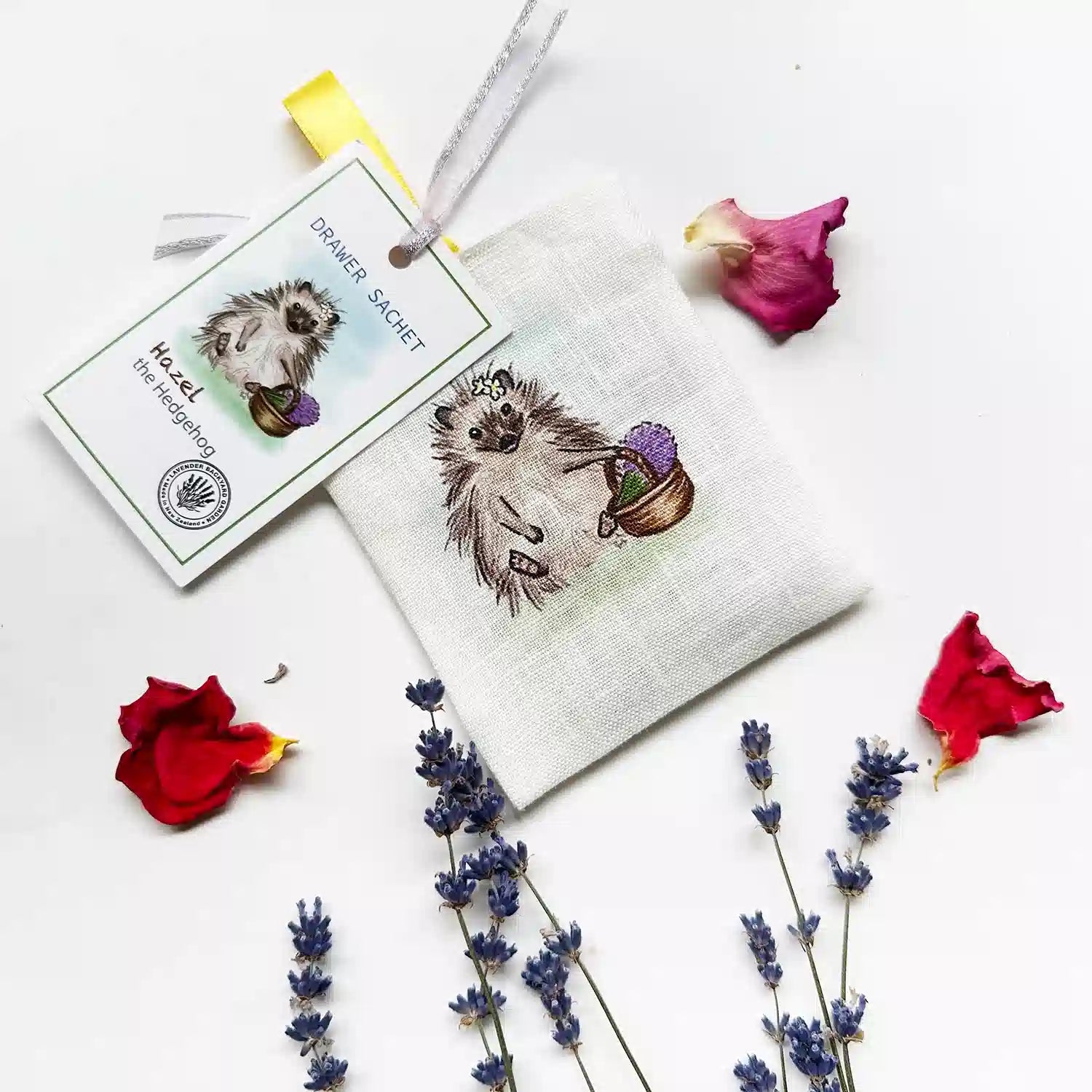 Hedgehog farm animal scented linen sachet with a background of dried lavender flowers and rose petals.