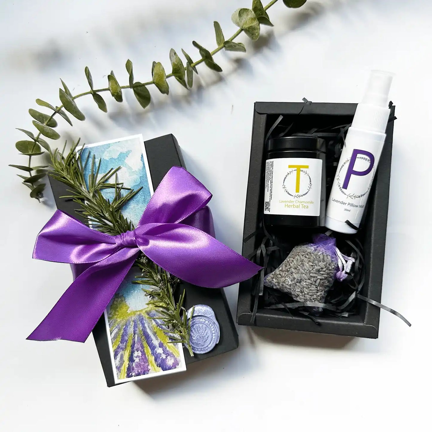 Indulgent Relaxing Day for Mother Gift Set featuring chamomile lavender tea, travel-sized pillow mist, and a lavender sachet, elegantly wrapped in a black gift box with a purple ribbon, accompanied by a lavender field bookmark and dried herbs.