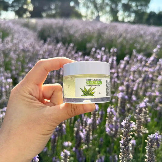 Lavender Aloe Vera Face Scrub, held by hand against a purple lavender field at sunset at Lavender Backyard Garden, New Zealand.