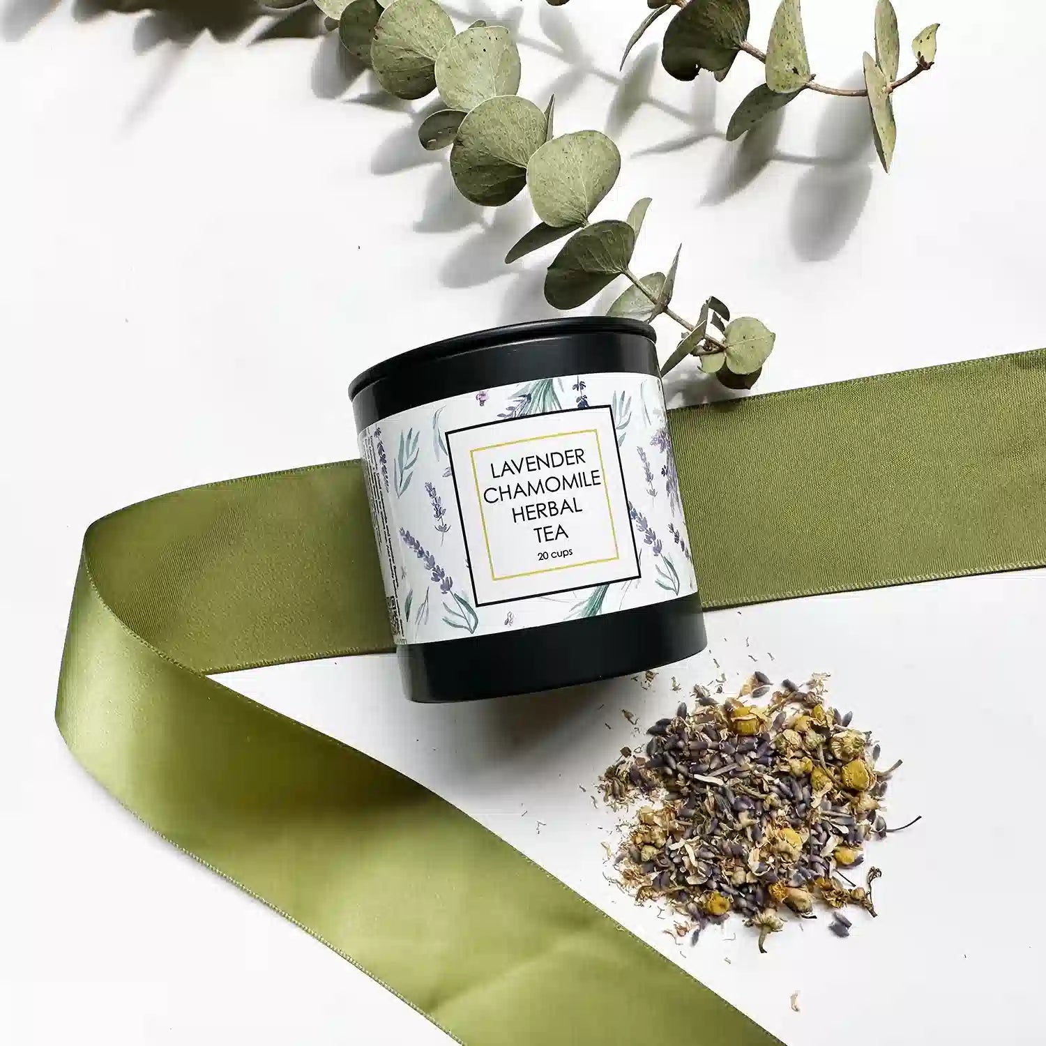 Lavender & Camomile Herbal Tea - Loose Leaf, with tea leaves displayed in the background, accented by a green ribbon and eucalyptus leaves.