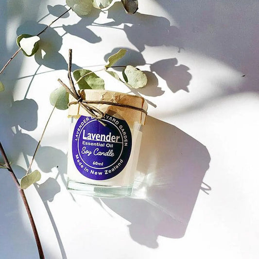 Lavender essential oil soy candle in a glass jar, with a background of eucalyptus and soft, beautiful light shadows.