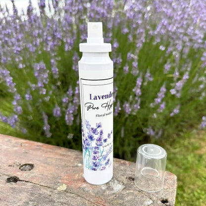 Bottle of lavender floral water (pure hydrosol) placed on a wooden bench with a blooming lavender field in the background at Lavender Backyard Garden, NZ.