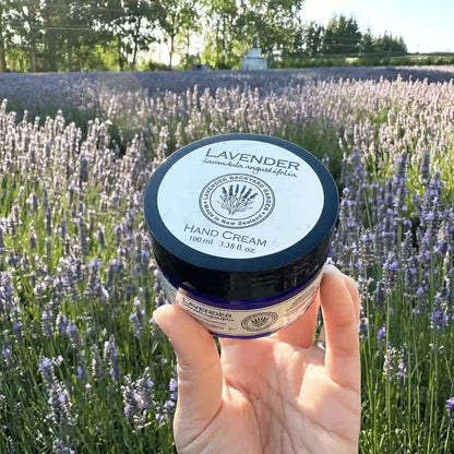 Close-up view of lavender hand moisturizer, holding by hand against blooming lavender field at Lavender Backyard Garden, NZ.