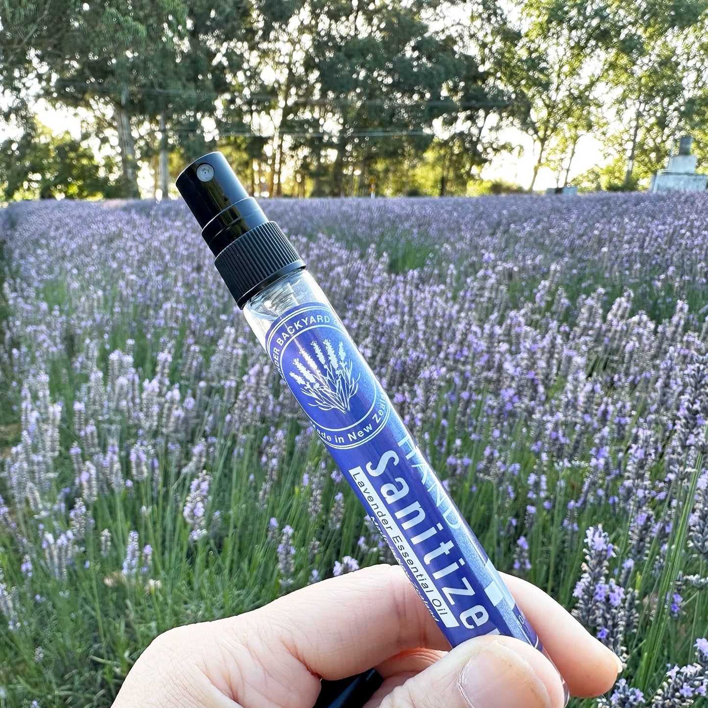 Lavender Hand Sanitiser with open lid, showcasing the nozzle, against a backdrop of blooming lavender at Lavender Backyard Garden, NZ.