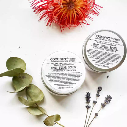 Close-up of Lavender Hand Sugar Scrub with Coconut Oil and Hibiscus, set against a background decorated with dried eucalyptus and lavender flowers.