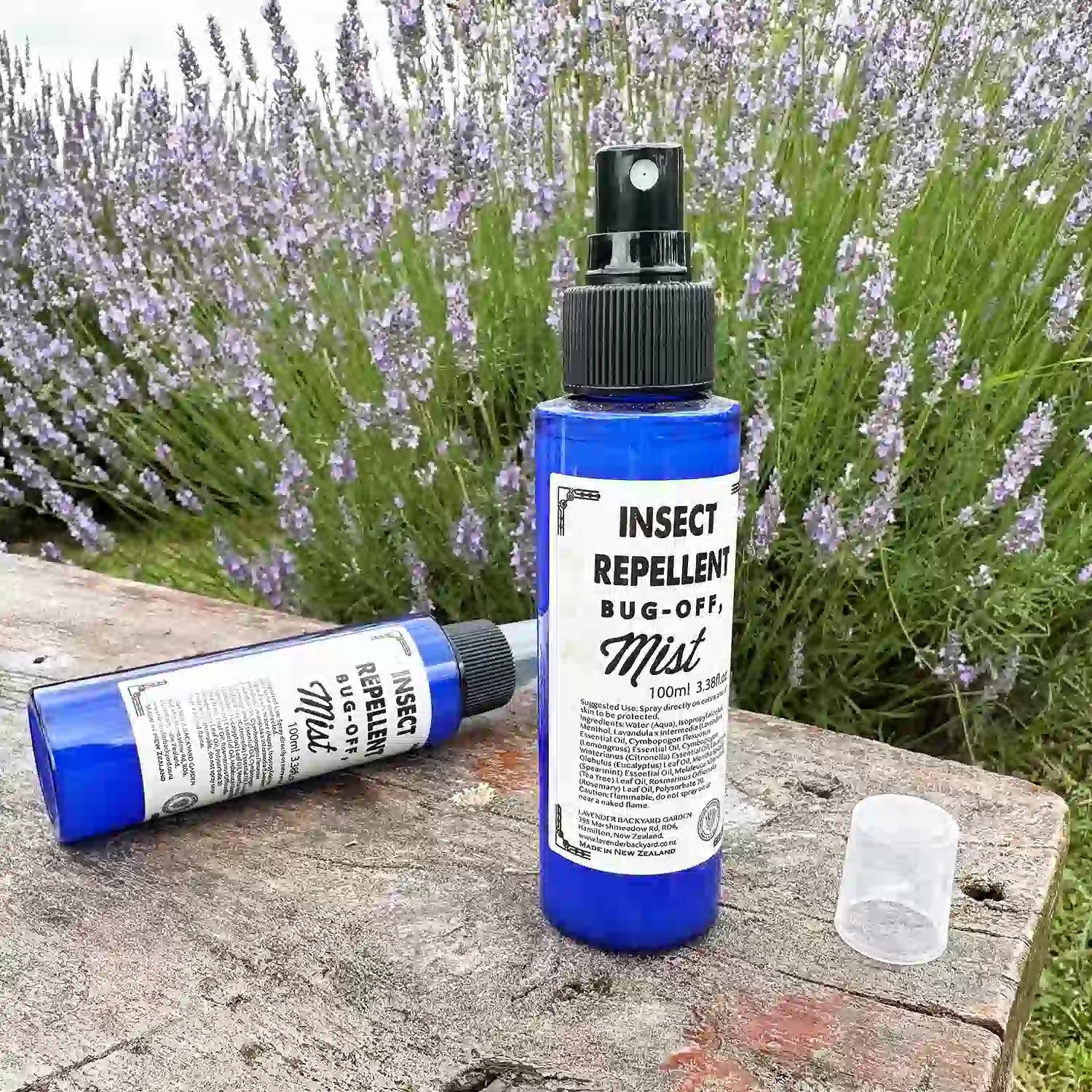 Lavender insect repellent spray, scented by essential oils, displayed on a wooden bench with a vibrant lavender field in the background at Lavender Backyard Garden, NZ.