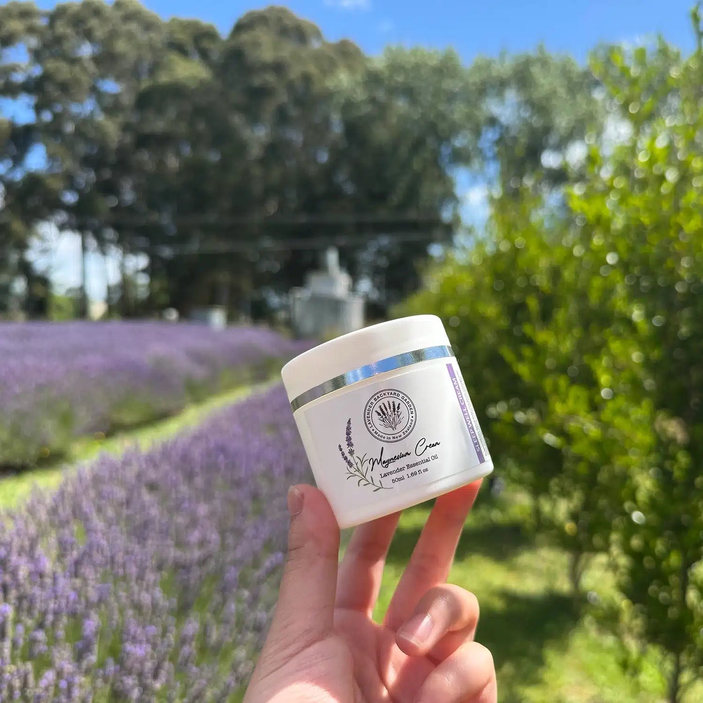 Lavender Magnesium Sleep Cream, scented by essential oils, displayed against the background of a lavender field at Lavender Backyard Garden, NZ.