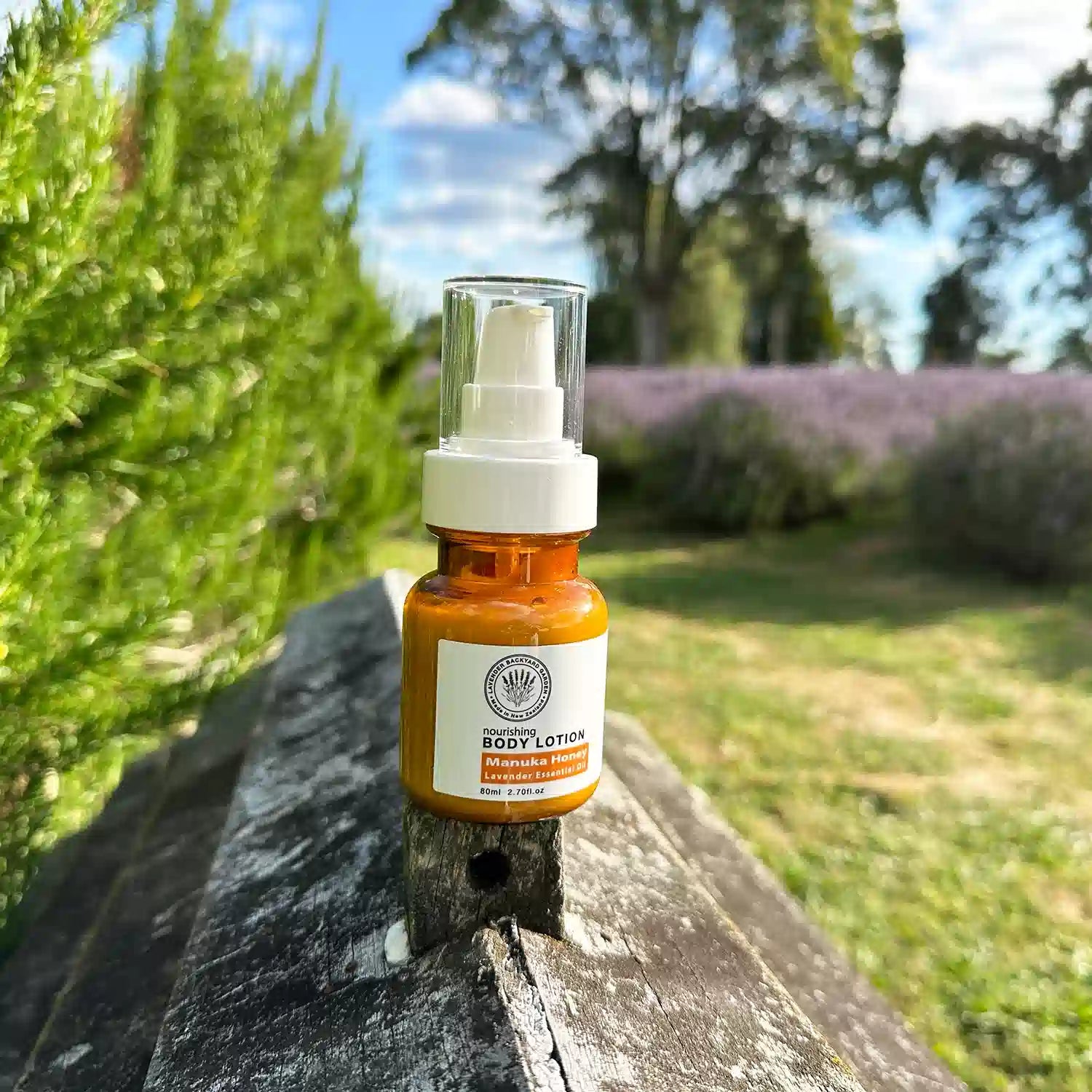 Lavender Manuka Honey Lotions Moisturisers, placed on a beehive against rosemary bushes and purple lavender rows at Lavender Backyard Garden.