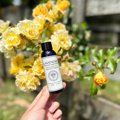 Lavender massage oil, scented by essential oils, held by hand with a yellow rose background.