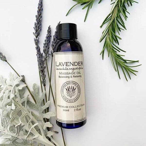 Lavender massage oil to relieve stress with rosemary, lavender flowers and other herbs in the background.