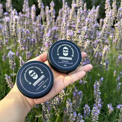 Two shaving soap scented by lavender fragrance tins, held by hand against lavender blooming flowers.