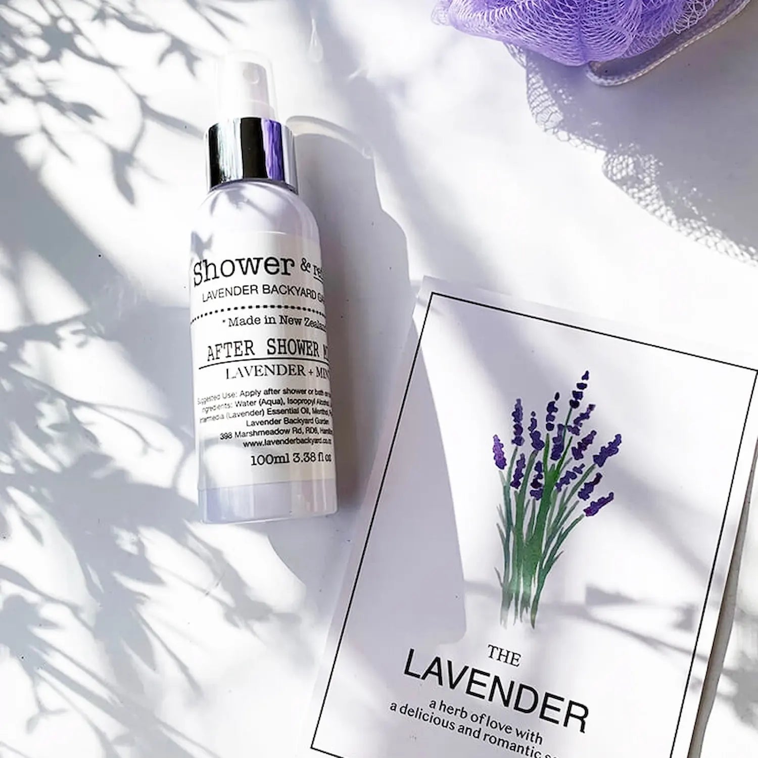 Lavender & Mint Daily Moisturizing After-Shower Mist, cooling spray set against a background of a lavender greeting card and soft bath cloth, emphasizing its refreshing and hydrating properties.