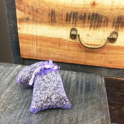 Drawer sachet bag filled with lavender dried flower buds against a wooden drawer background.