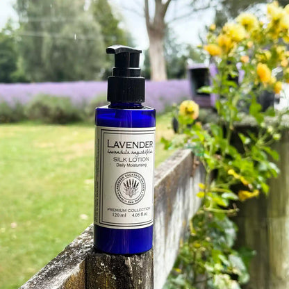 Lavender Silk Body Lotion scented by essential oils, displayed with a background of lavender field and yellow roses.