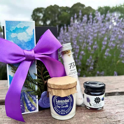 Lavender Sweet N' Divine Lavender Gift Box featuring Floral Bath Salts Tube, Blueberry Jam with a hint of Lavender, Lavender Essential Oil Candle 60ml, and Lavender Field Bookmark displayed against blooming lavender bushes.