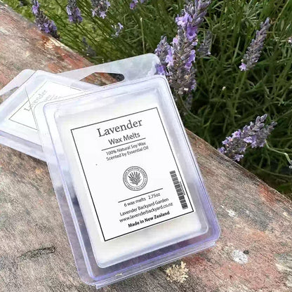 Lavender wax melt scented with lavender essential oil, placed on a wooden surface with a backdrop of blooming lavender flowers.