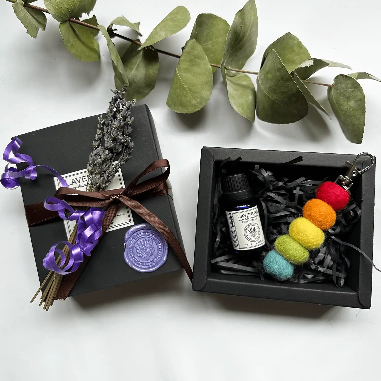 Lovely Gift Box for Secret Santa containing a felt ball diffuser and pure lavender essential oil from a New Zealand lavender farm, wrapped in a black gift box with dried lavender flowers.