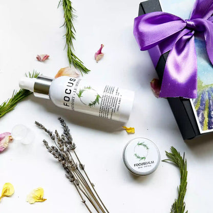 Close-up look of "Lavender & Rosemary Focus Balm, Focus Aromatherapy Spray with Pure Essential Oils" with rosemary leaves, dried lavender flowers, and rose petals as background decor, accompanied by a purple ribbon gift box.