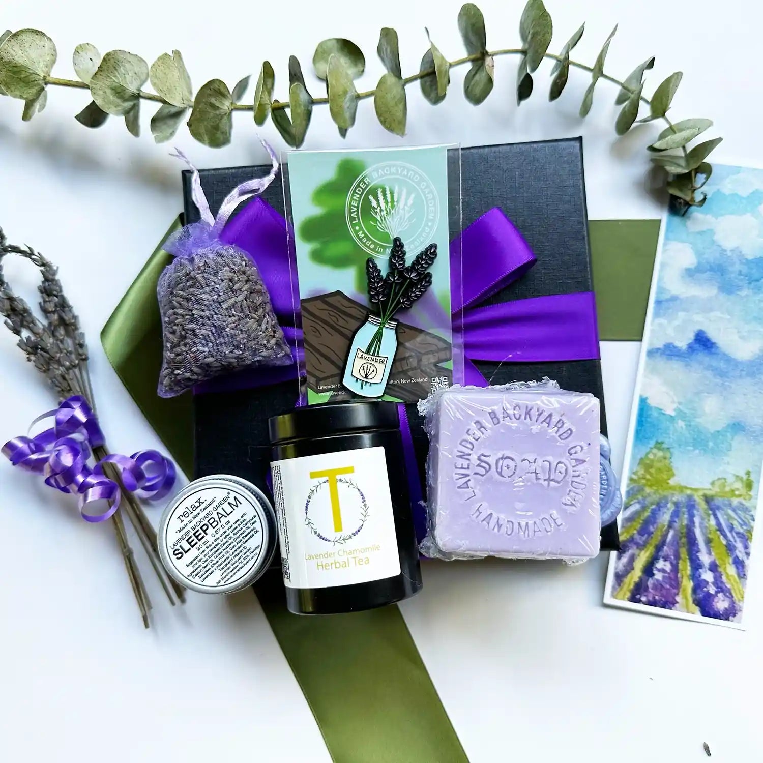 The Mother's Special Day Spoil Kit includes lavender chamomile herb tea, lavender sleep balm, handmade soap, lavender fridge magnet, and a dried lavender sachet, all elegantly presented in a purple ribbon black gift box.