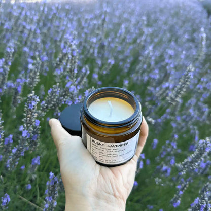 Opened lid of Musky Lavender Coconut Wax Candle, showcasing the inner texture of the candle, set against a blooming lavender field at Lavender Backyard Garden, NZ.