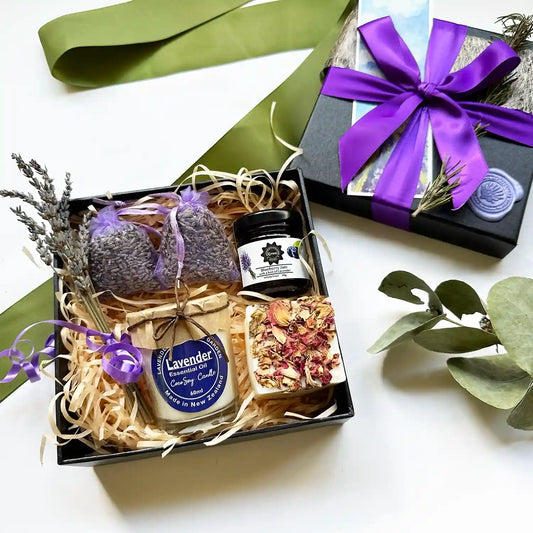 Relaxing lavender gift set featuring lavender blueberry jams, a soy candle scented with lavender essential oil, handmade soap, and a lavender sachet, elegantly wrapped with a purple ribbon and accompanied by a lavender field bookmark.