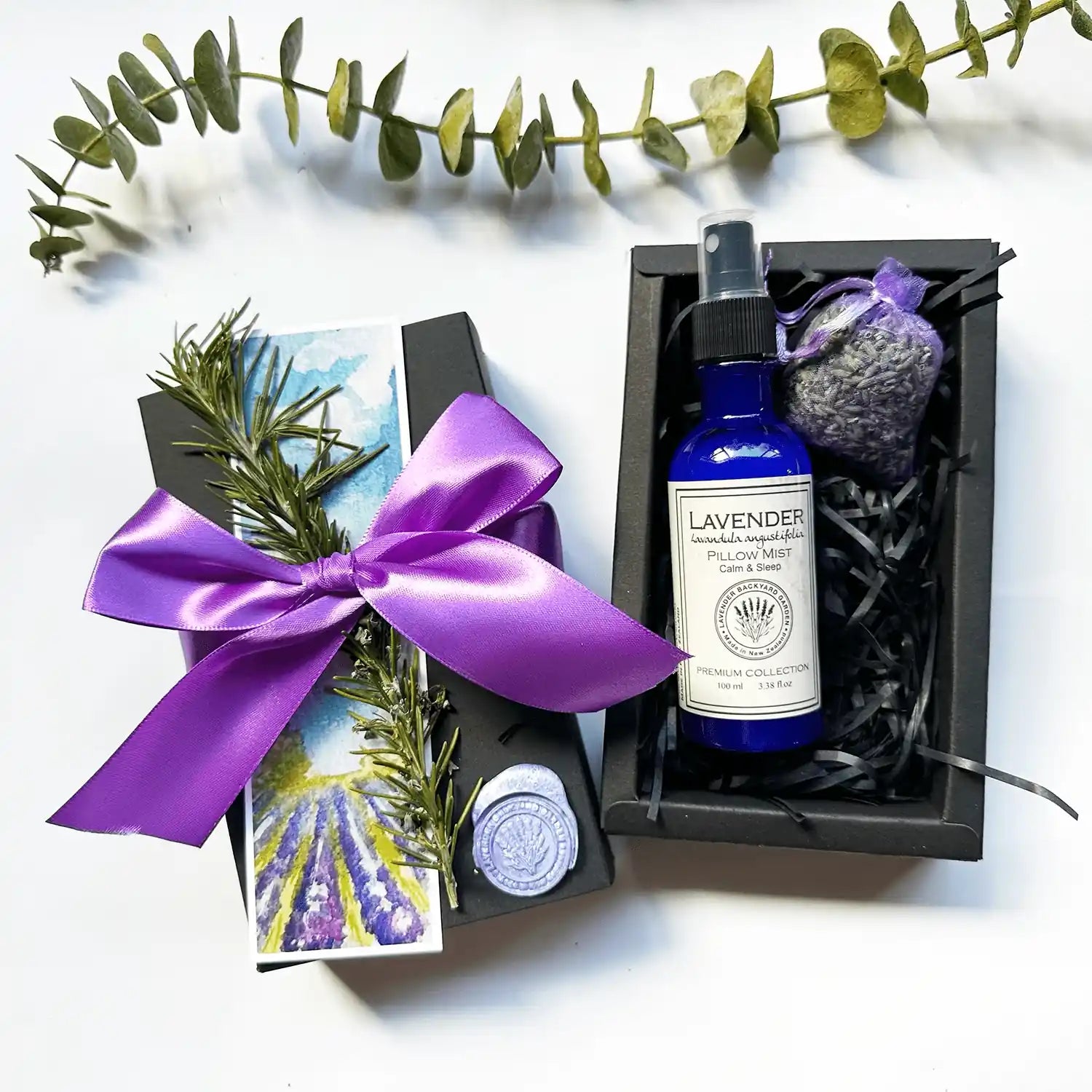 Restful Night Sleep Gift Box packaged in a black gift box with a purple ribbon, featuring a sleep spray scented with lavender essential oil, a lavender drawer sachet, and a lavender field bookmark.