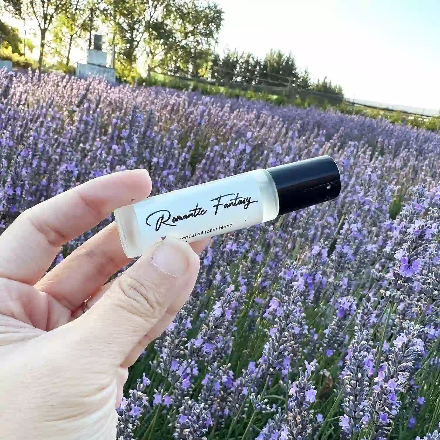 Romantic Fantasy Natural Perfume scented by essential oils, held by hand against a purple sea of blooming lavender.