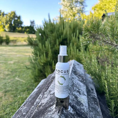 Rosemary Lavender Focus Mist bottle placed on an old beehive with the background of rosemary bushes at Lavender Backyard Garden, NZ.