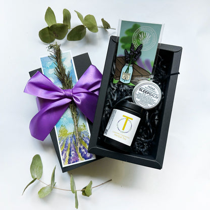 Small Thoughtful Lavender Gift set wrapped in a purple ribbon gift box, featuring lavender chamomile tea for sleep, a scented sleep balm made with essential oils, a lavender fridge magnet, and a lavender field bookmark.