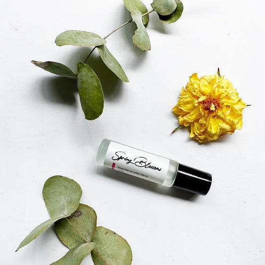 Spring Blossoms Essential Oil Natural Perfume surrounded by vibrant yellow roses and fresh eucalyptus leaves, creating a refreshing and floral backdrop.