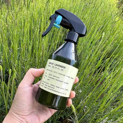 Sweet Amber Lavender Linen Spray over Bedding, with a background of an early-stage lavender field.