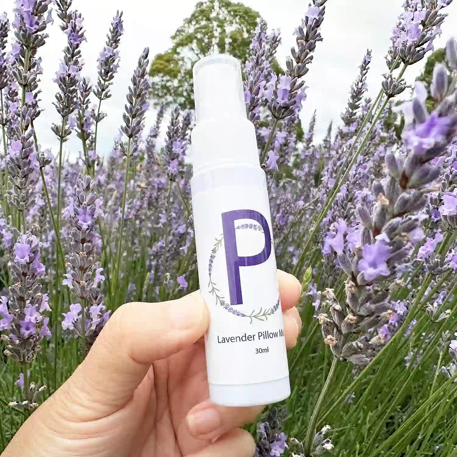 Travel-size sleep spray scented with lavender essential oil, set against the backdrop of a blooming lavender field at Lavender Backyard Garden NZ.