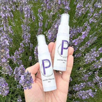 Two bottles of travel-size sleep spray placed on top of lavender flowers, with a soft lavender scent.